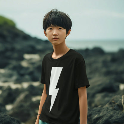 Person wearing a black t-shirt with a white lightning bolt design, standing on a rocky landscape.