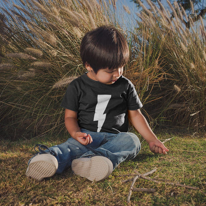Child sitting on grass with tall grasses in the background